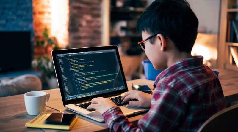 Young person coding on a laptop at home.